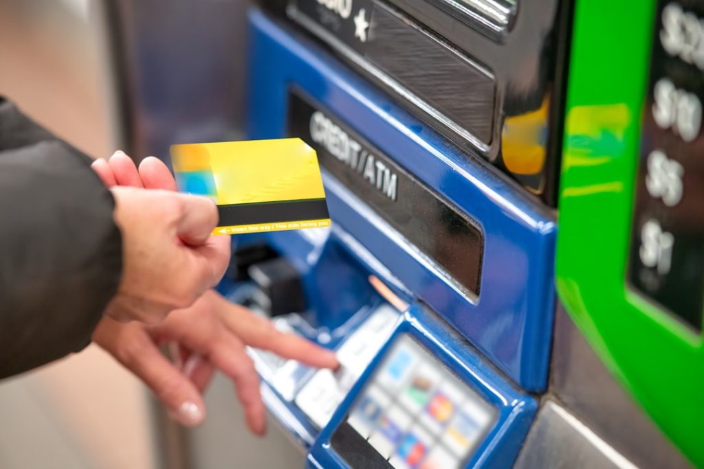 Person inserting a card into an ATM machine for a cash withdrawal or transaction.