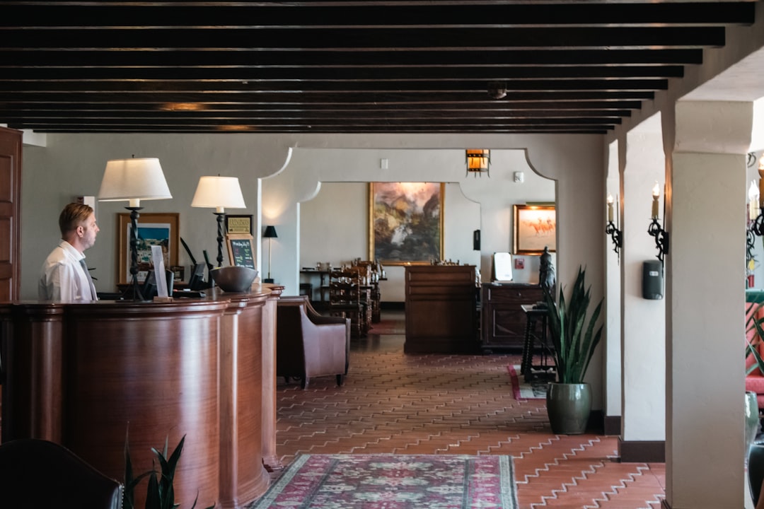 Hotel lobby reception area with a curved wooden counter and a staff member in a white shirt behind it.