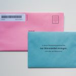 Pink voting envelope overlapped by a blue ballot card with German instruction to insert only the ballot paper.