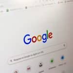 Google homepage shown on a computer screen with a colorful logo and search bar central to the page.