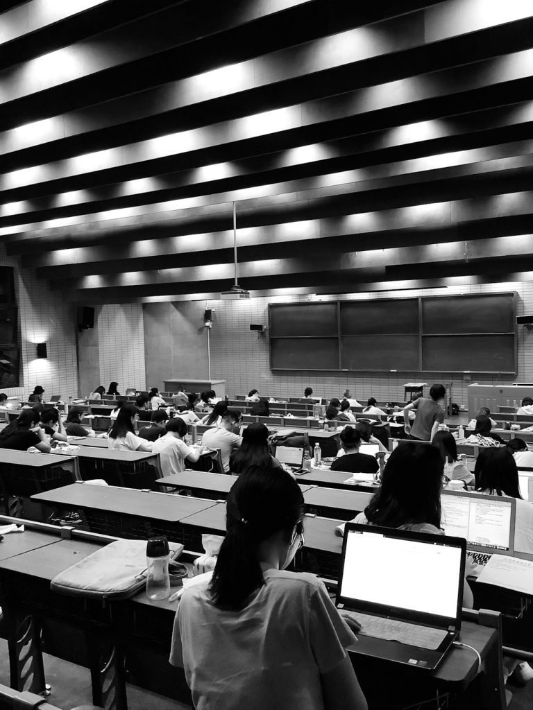A large lecture hall filled with students at desks, many using laptops.