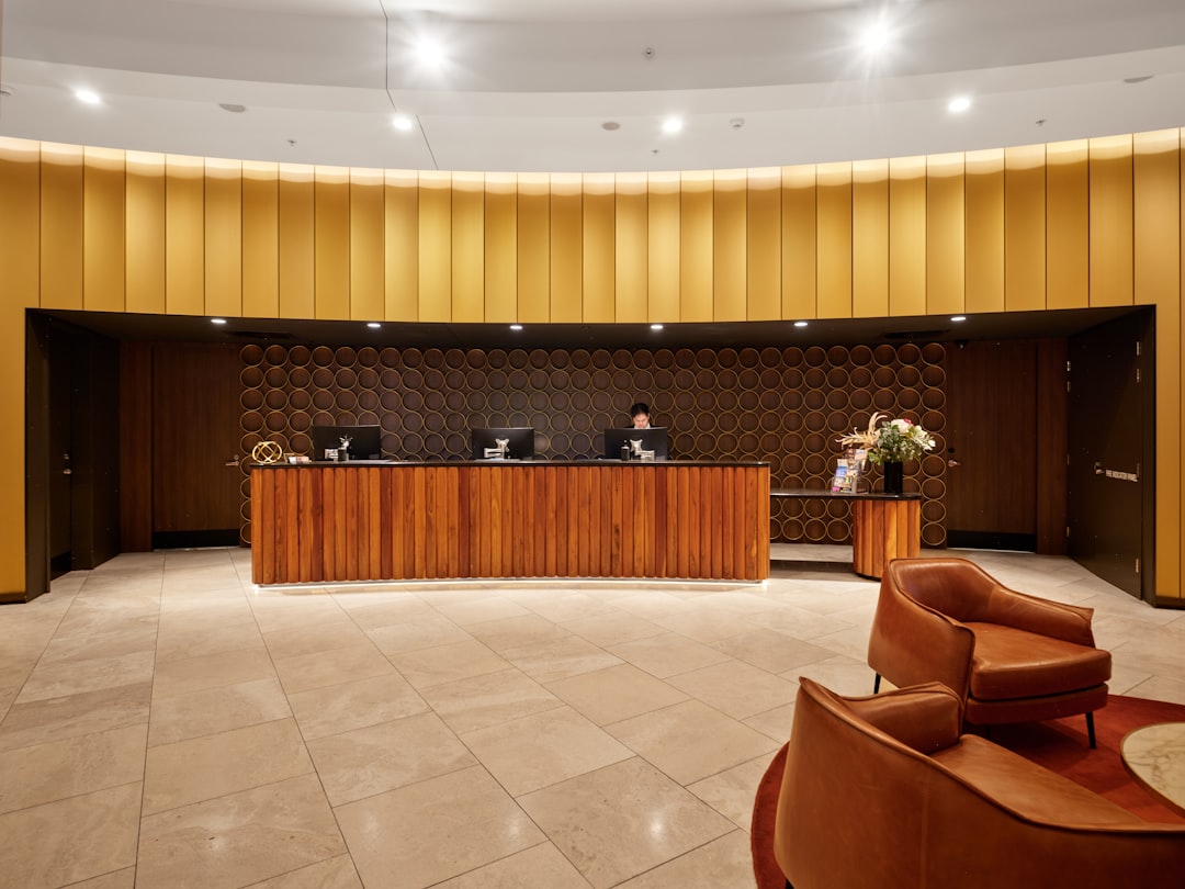 Reception desk in a warmly lit hotel lobby with a rounded wood counter and circular wall panels behind it.