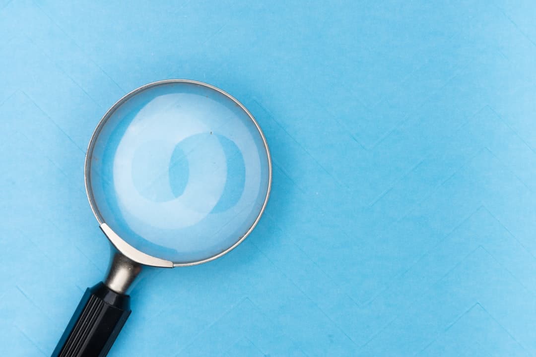 Close-up of a magnifying glass with a black handle on a blue background
