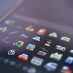 Close-up of a smartphone home screen with a grid of colorful app icons blurred in the background.