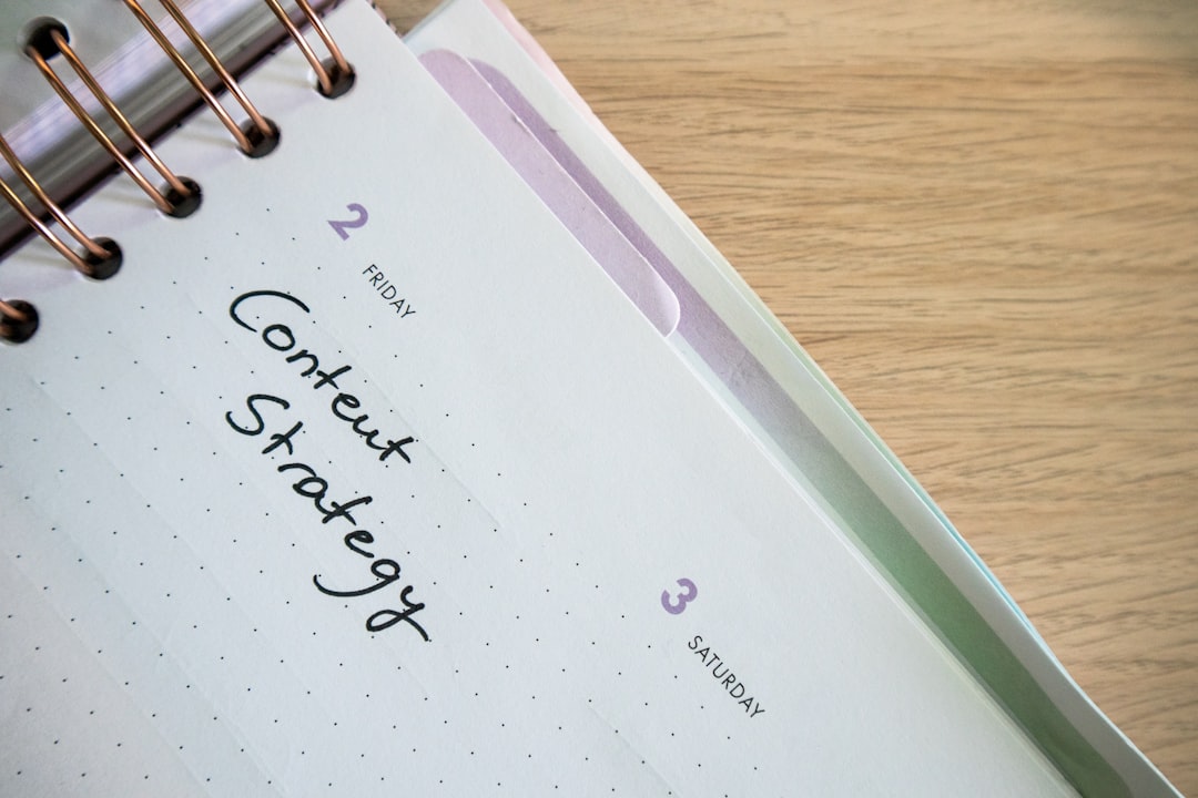 Close-up of a spiral-bound planner open to a page labeled 'Content Strategy' with dates Friday 2 and Saturday 3 on a wooden desk.