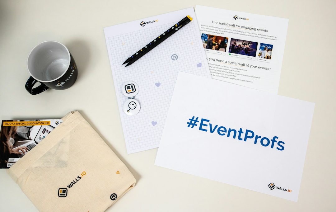Desk with Wall.io event materials: tote bag, notebook with pencils, mug, brochures, and a large '#EventProfs' card on a light surface.