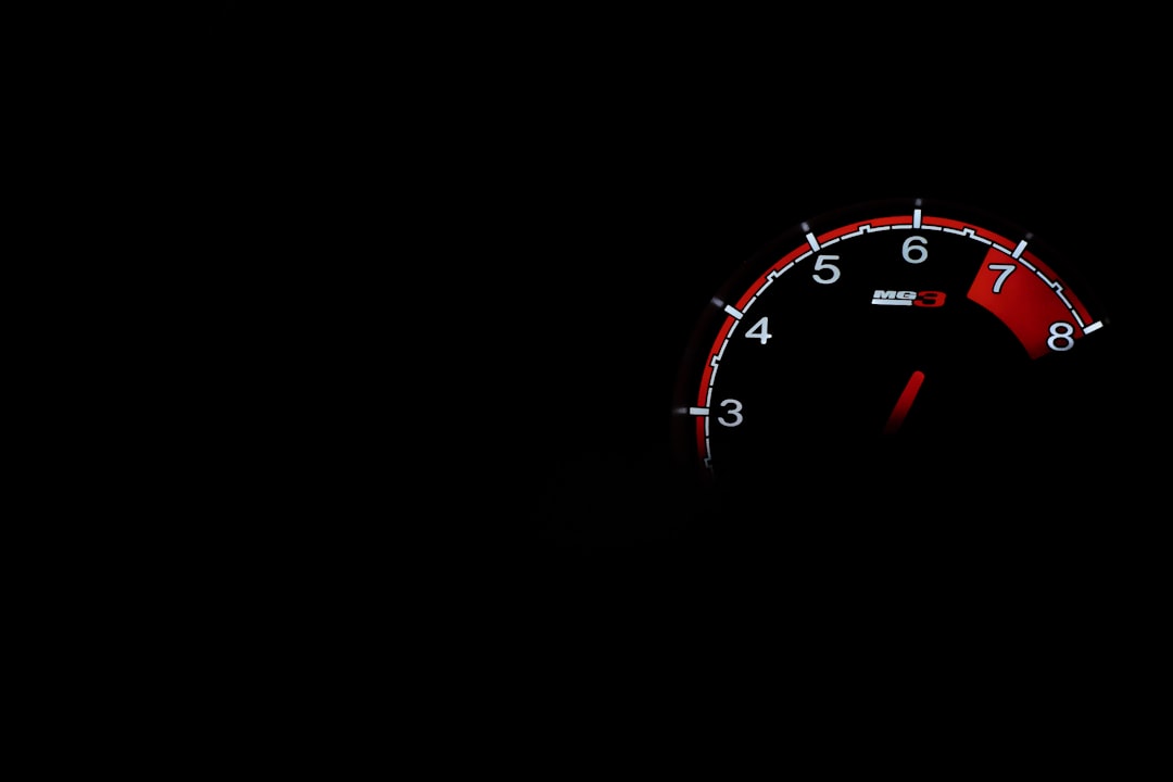 Close-up of a car tachometer with a red arc from 6 to 8, needle near 7 on a black background