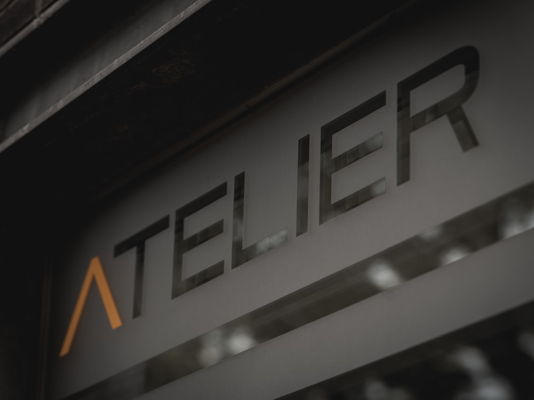 Close-up of a storefront sign reading 'ATELIER' with an orange chevron accent to the left.