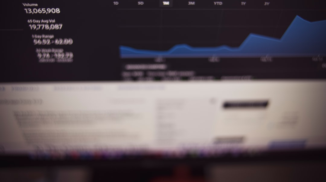 Blurred monitor displaying a dark dashboard with a blue line chart and unreadable side text; chart area is prominent but details are not legible.