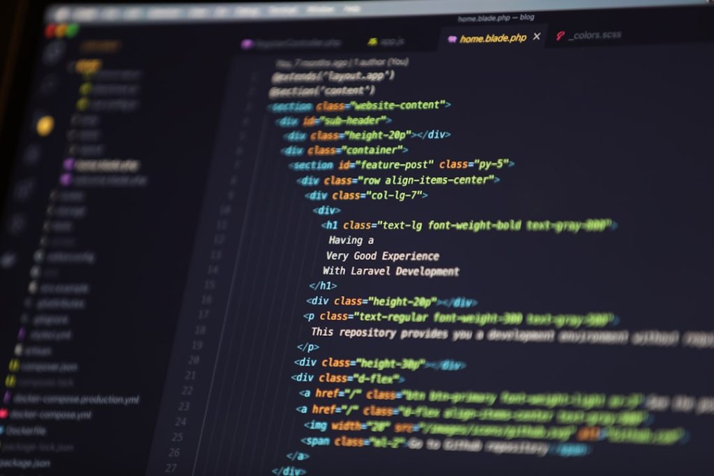 Close-up of a dark-themed code editor on a monitor with colorful HTML/CSS syntax highlighting.