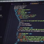 Close-up of a dark-themed code editor on a monitor with colorful HTML/CSS syntax highlighting.