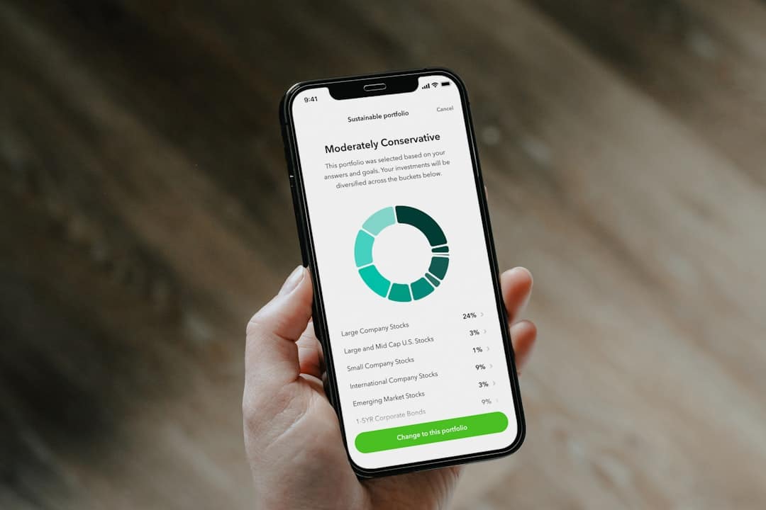 Hand holding a smartphone displaying a moderately conservative investment portfolio with a teal donut chart.