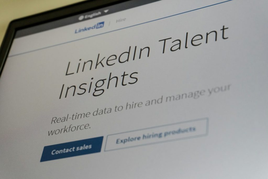 LinkedIn Talent Insights webpage on a monitor, showing the tagline 'Real-time data to hire and manage your workforce' and a 'Contact sales' button.