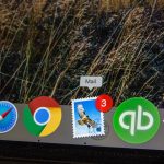 Mac desktop dock with app icons including Mail, Chrome, Safari, a postage-stamp style mail icon with a 3-notification badge, QuickBooks, and a purple star app against a grassy wallpaper.