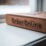 Cardboard delivery box on a windowsill with 'Order Online' branding visible