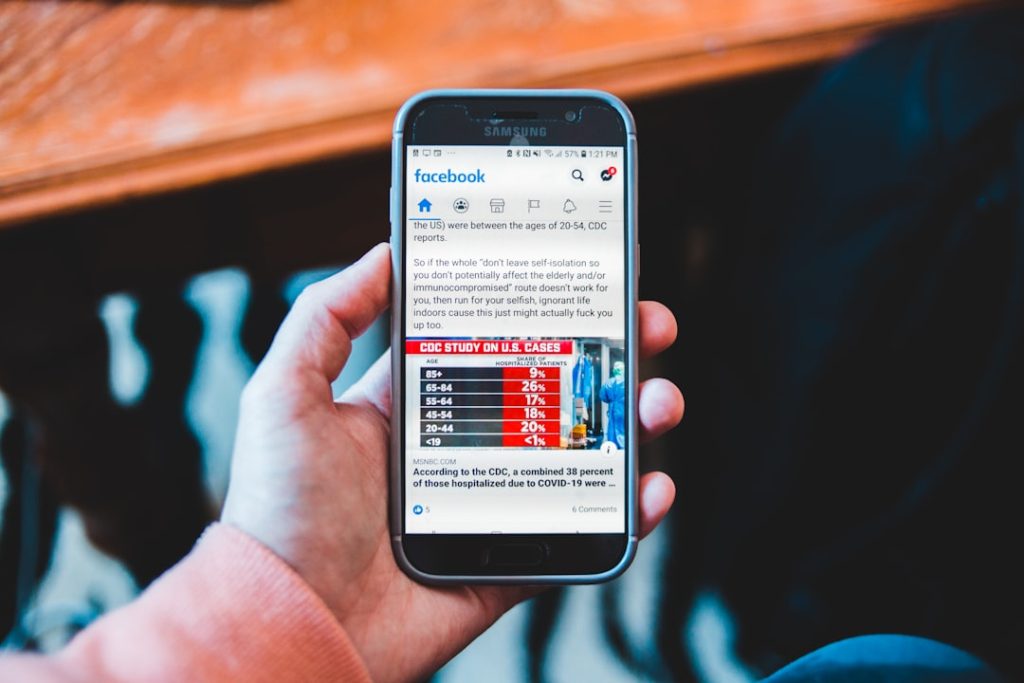 Hand holding a blue smartphone displaying a Facebook feed with a CDC study infographic on screen.