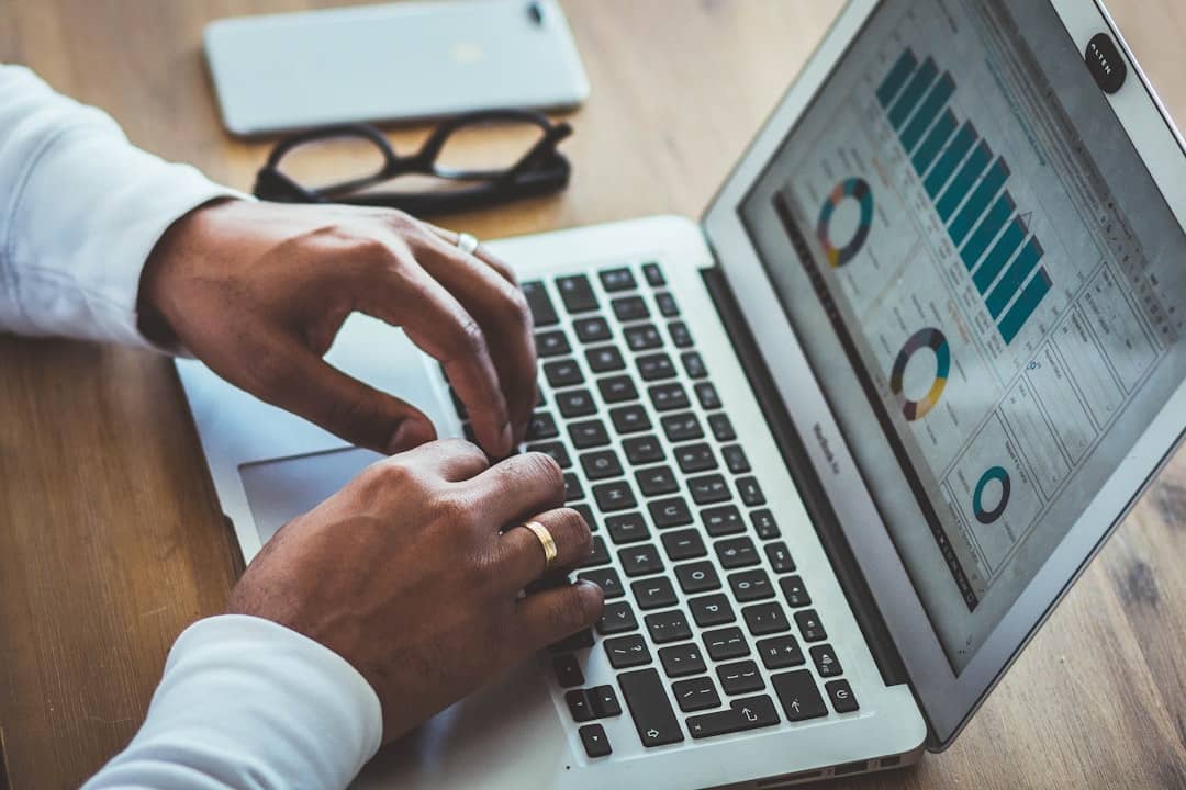 Hands typing on a silver laptop displaying analytics charts on screen.