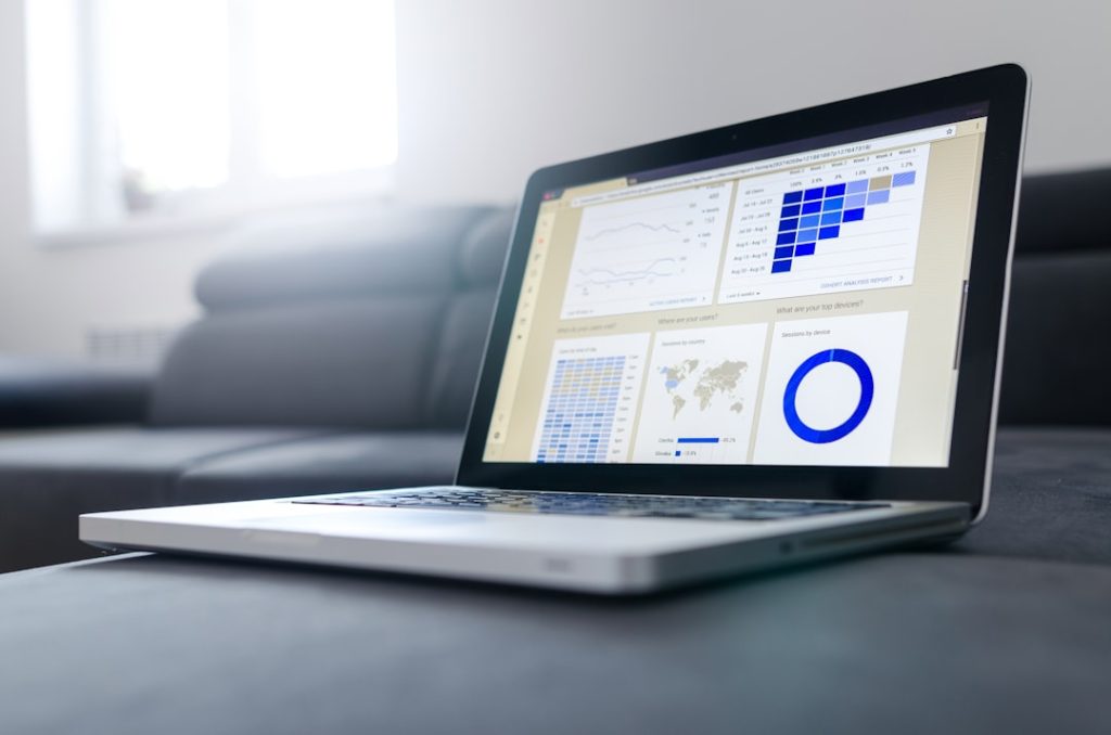 Laptop on a coffee table displaying analytics dashboards and charts on the screen