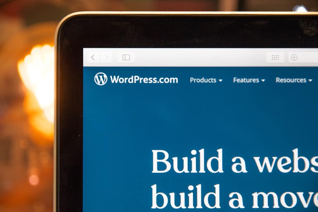 Laptop screen showing WordPress.com homepage with a blue banner and large white text reading 'Build a website'