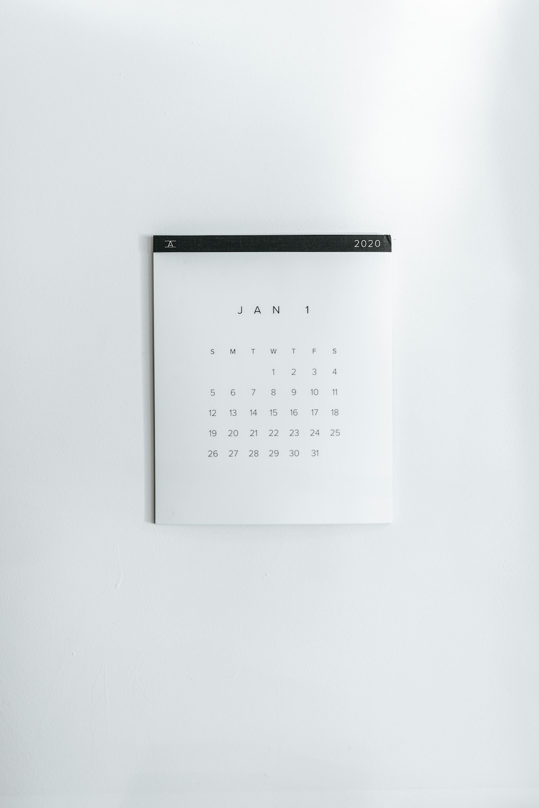 Minimalist white calendar page showing January 1, 2020 against a white wall.