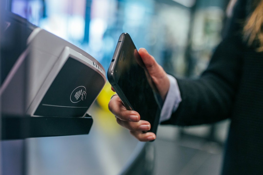 Customer uses a smartphone to pay with a contactless payment terminal, tapping the device on the reader.