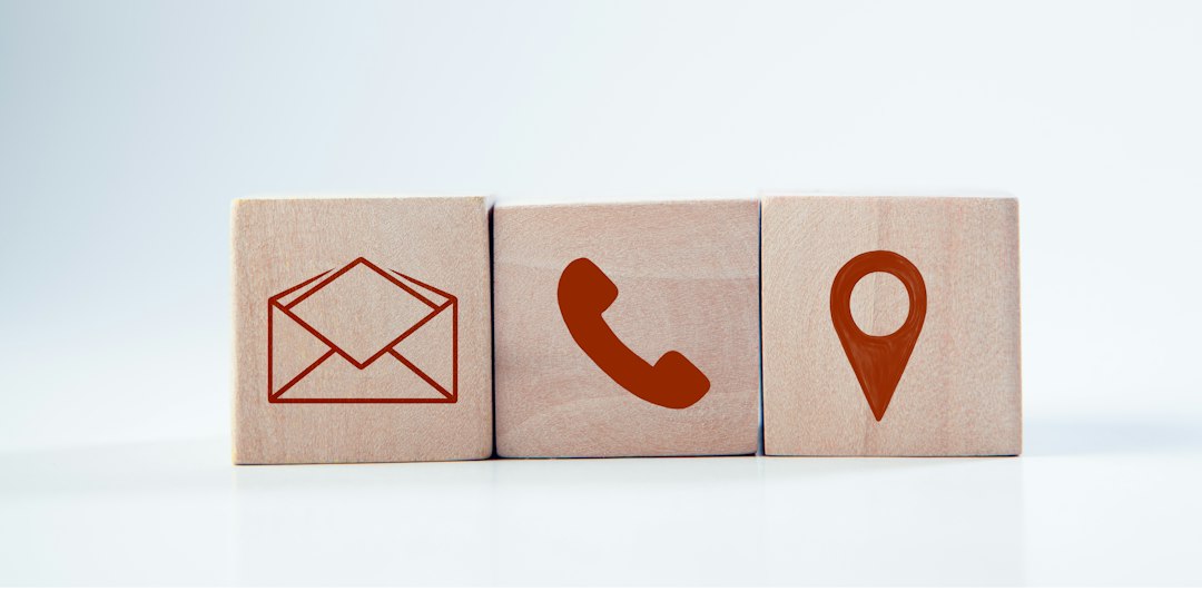 Contact options shown as icons on wooden blocks: email envelope, phone handset, and location pin on a light background.