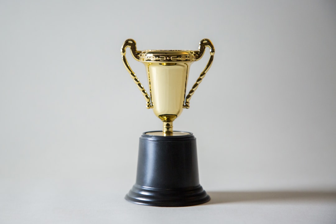 Gold trophy with black pedestal on a neutral background, symbolizing victory or achievement.