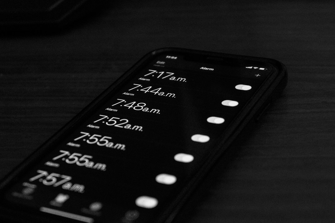 Smartphone screen showing several alarm times in the morning on a dark display.