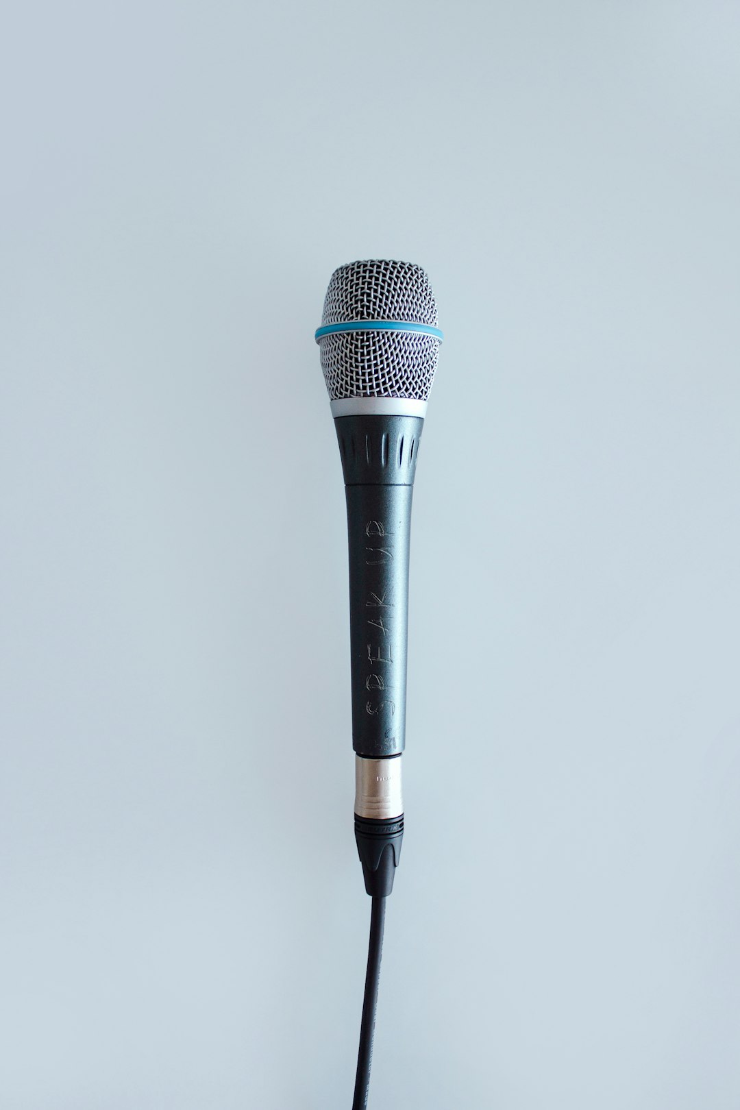 Dynamic microphone on a stand against a pale gray background, ready for recording.