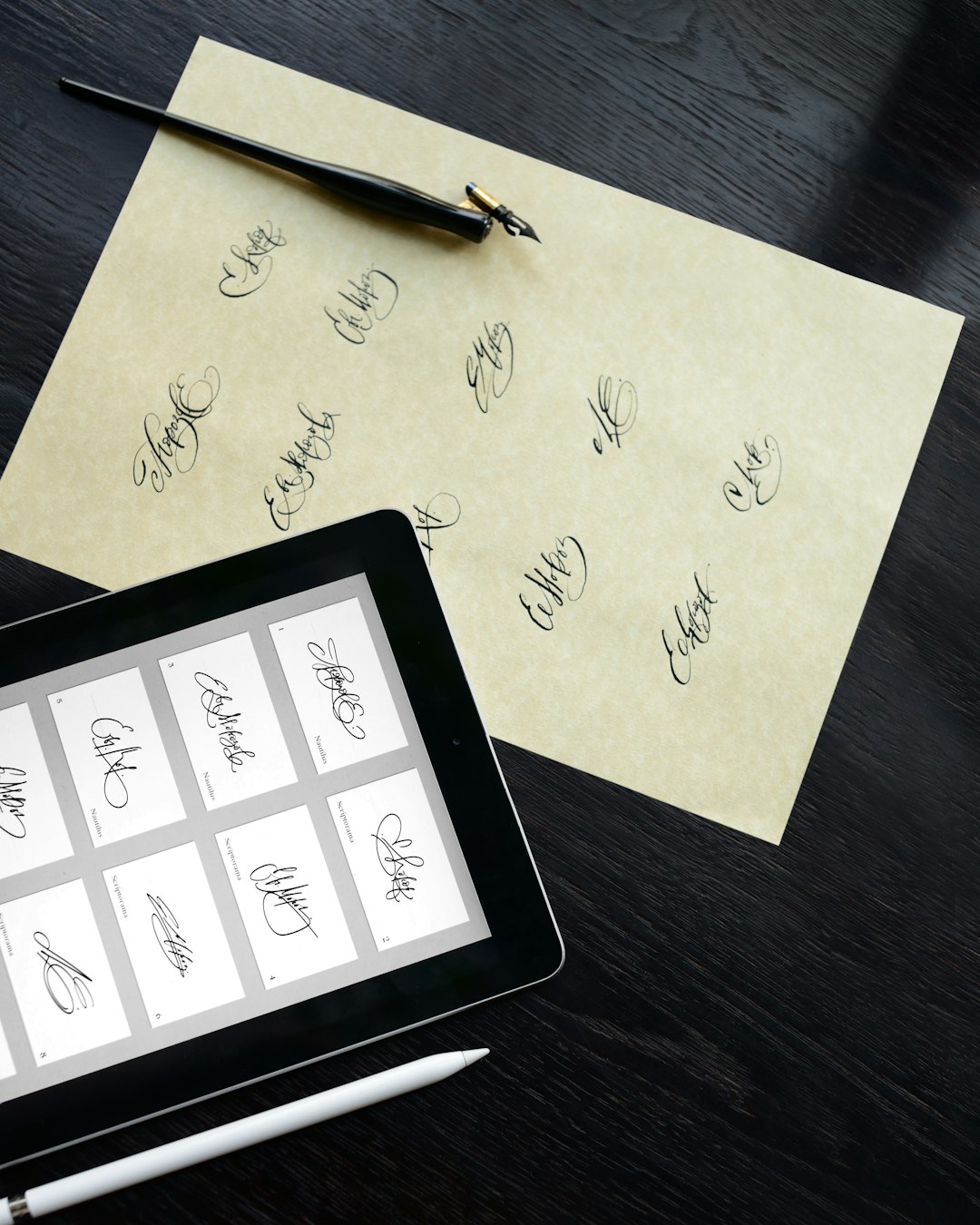 Tablet showing a grid of signature samples on a dark desk with a white stylus nearby and a parchment with handwritten signatures, plus a fountain pen legible at top edge.