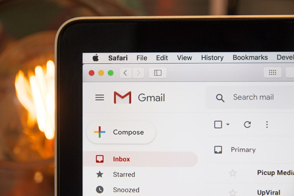 Laptop screen showing Gmail inbox with Compose button and red Inbox highlight, Safari menu visible at the top