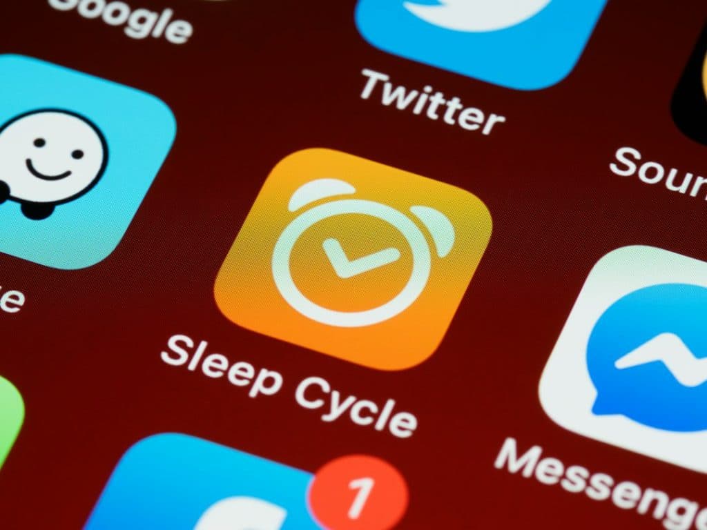 Sleep Cycle app icon on a phone home screen, orange square with a white alarm clock.