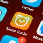 Sleep Cycle app icon on a phone home screen, orange square with a white alarm clock.
