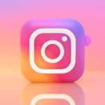 3D Instagram logo cube with the camera glyph on a pink–orange pastel gradient background with reflections