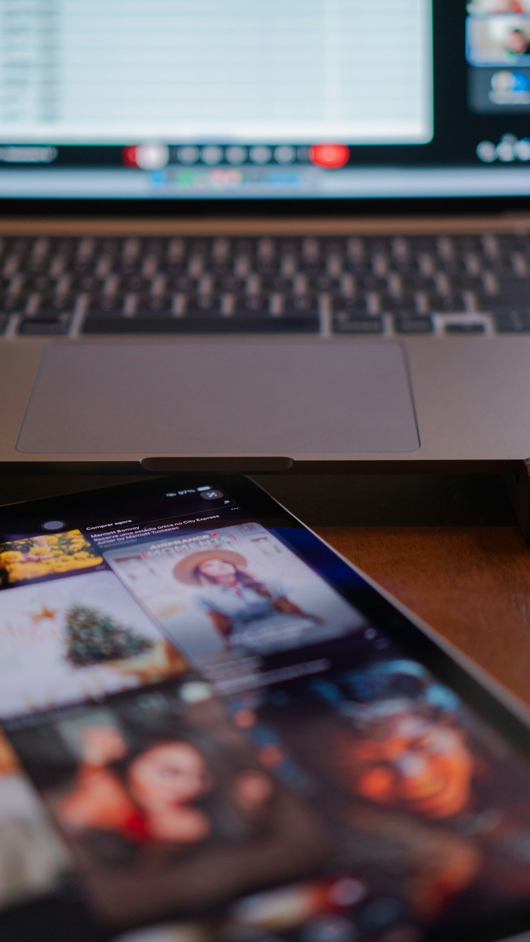 Laptop keyboard and large trackpad visible with a tablet in the foreground showing a colorful photo collage on its screen.
