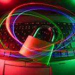 Laptop keyboard with a glowing padlock and swirling neon light trails, symbolizing cybersecurity and data protection.