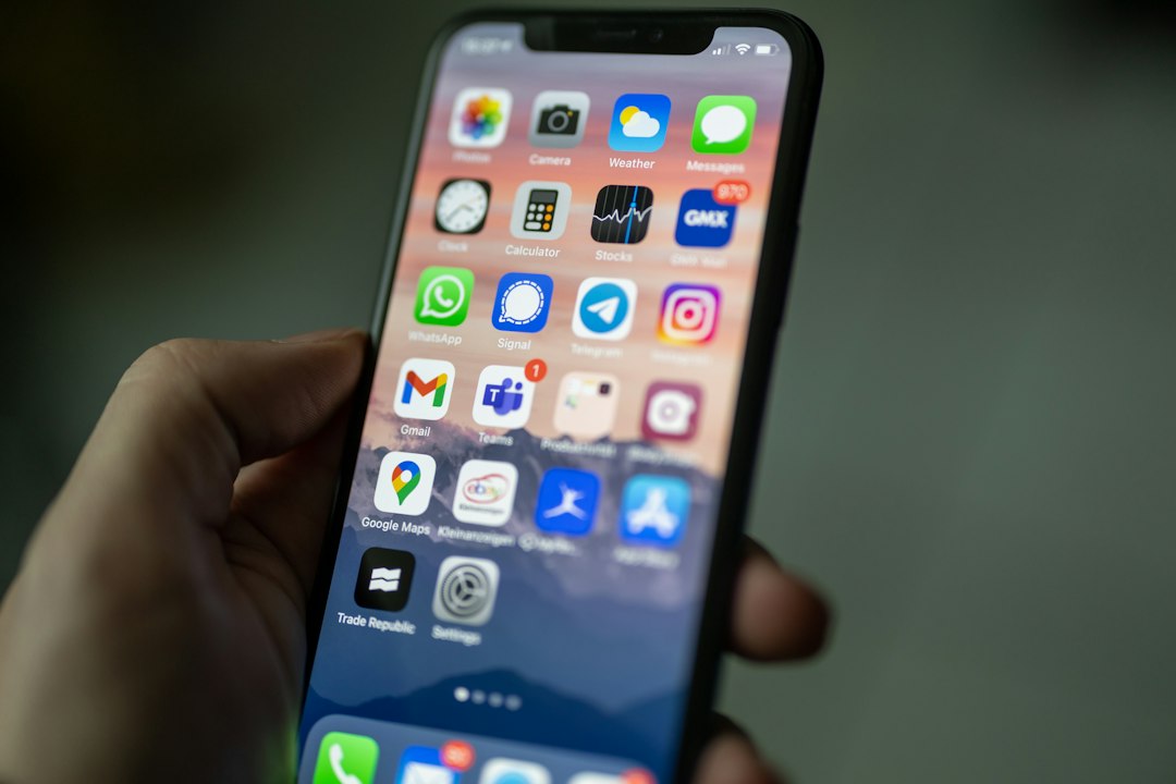 Hand holding a smartphone displaying a home screen full of colorful app icons.