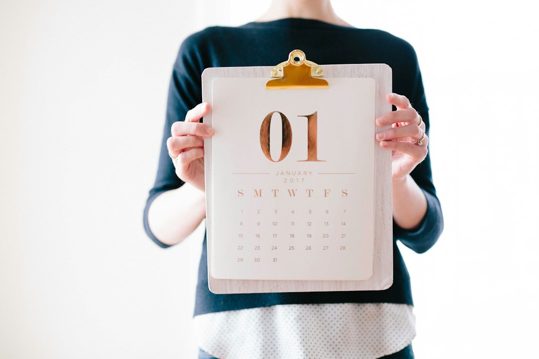 Person in a dark top holds a clipboard with a calendar page showing January 2017 and the date 01 prominent on it.
