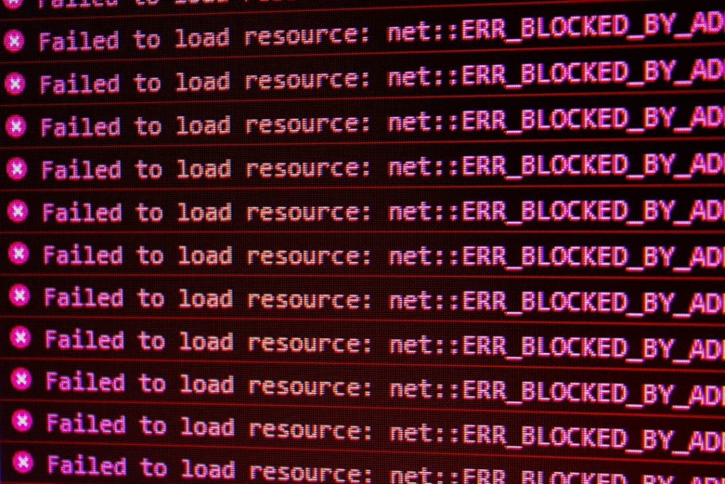 Multiple lines from a browser console showing 'Failed to load resource: net::ERR_BLOCKED_BY_AD' errors on a red background.