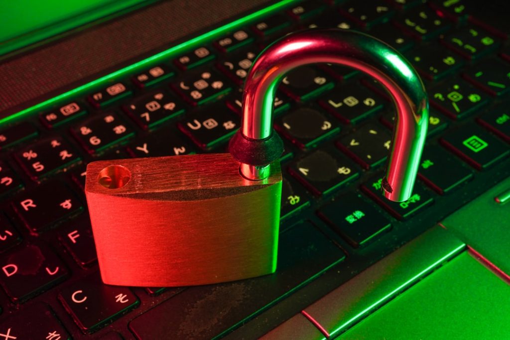 Padlock on a laptop keyboard bathed in red and green light, symbolizing cybersecurity and data protection.
