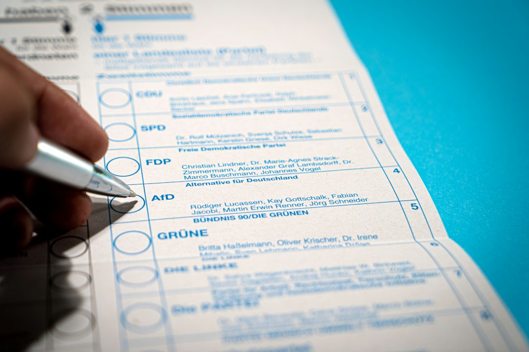Person marks a ballot with a pen on a German election paper showing party options like CDU, SPD, FDP, AfD, GRÜNE.