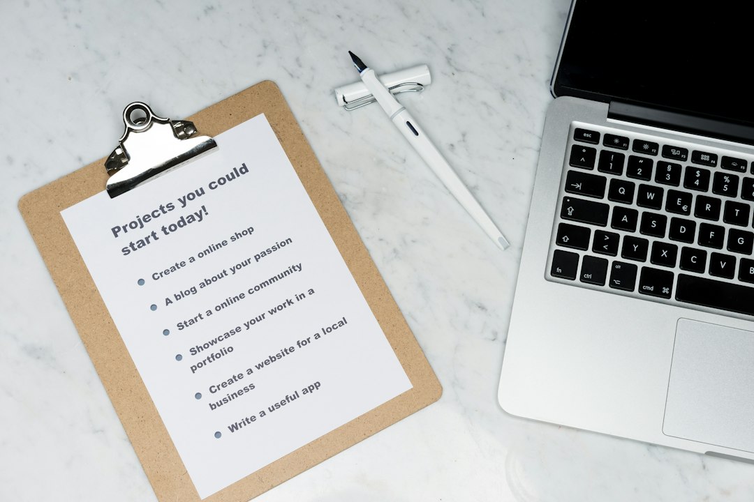 Clipboard holding a sheet titled 'Projects you could start today!' with a to-do list beside a white pen and a laptop on a marble surface.