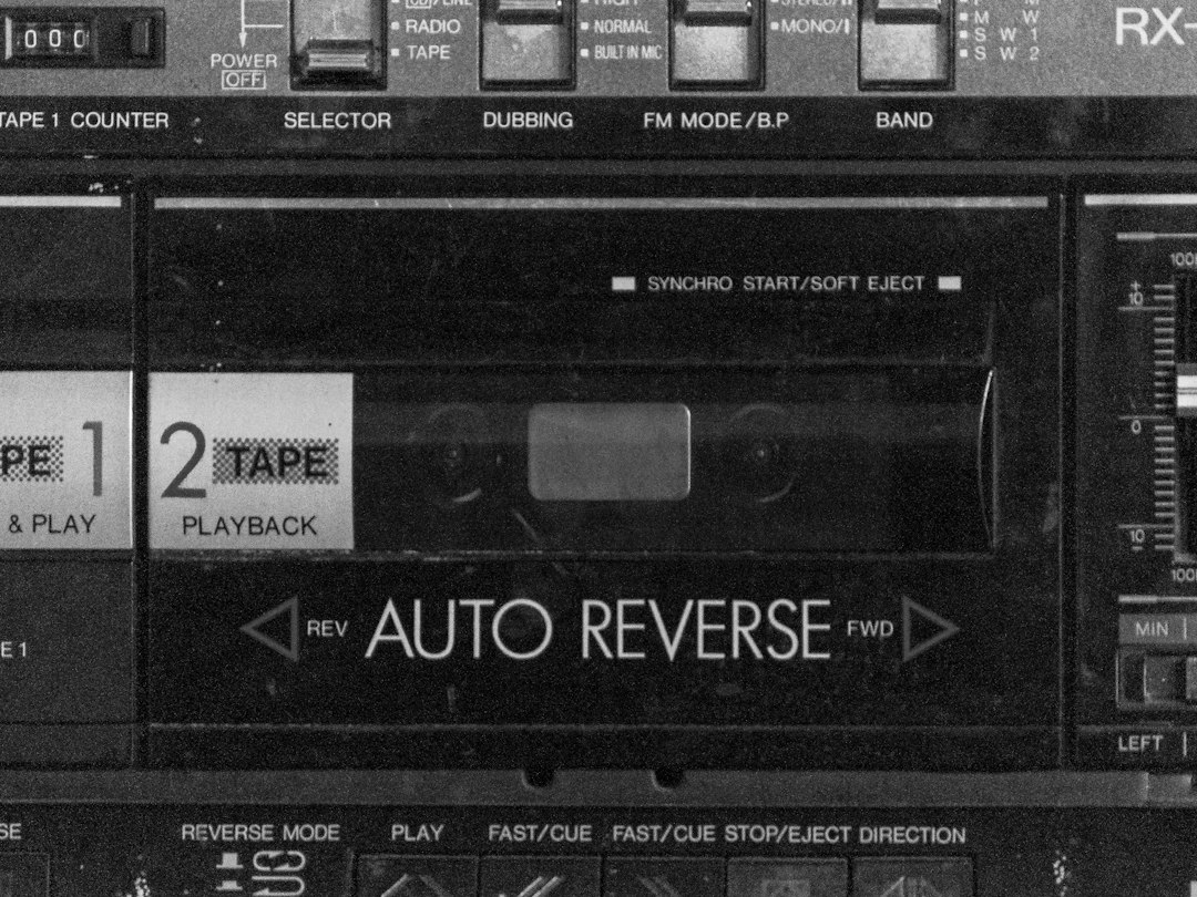 Close-up of a stereo cassette deck showing auto reverse label and two tape slots (Tape 1, Tape 2) with controls above and dials on the right side.
