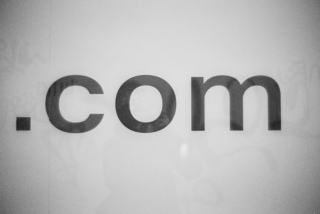 Large lowercase ".com" text across a pale, gray background (sign/logo style).