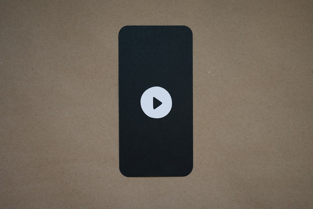 Play button centered on a dark rounded rectangle against a brown textured background (video placeholder)