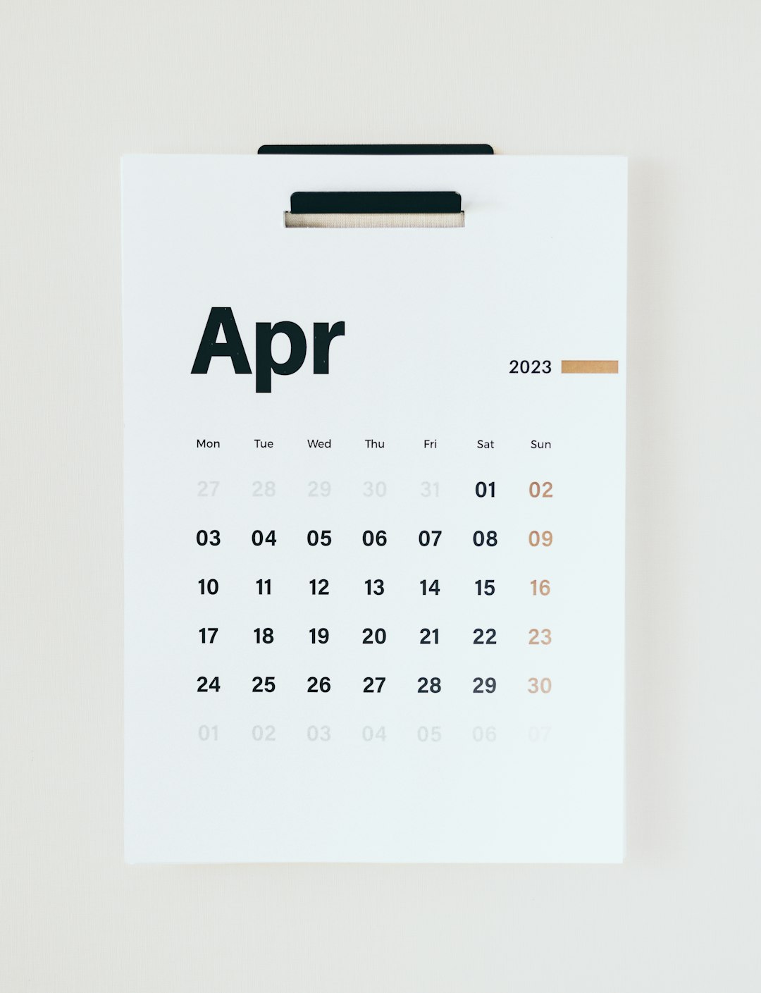 April 2023 calendar on a white clipboard, with a grid of days and bold dates