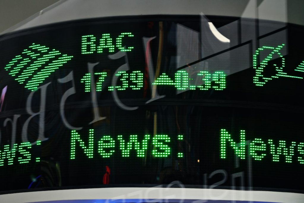 Close-up of a green LED ticker displaying 'News' and financial numbers on a glass surface.