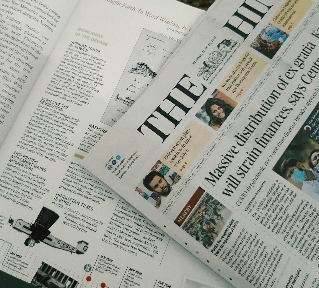 Close-up of overlapping newspapers with a large front-page headline and small photo thumbnails