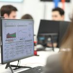 Office workspace with a monitor displaying charts and graphs on a data dashboard.