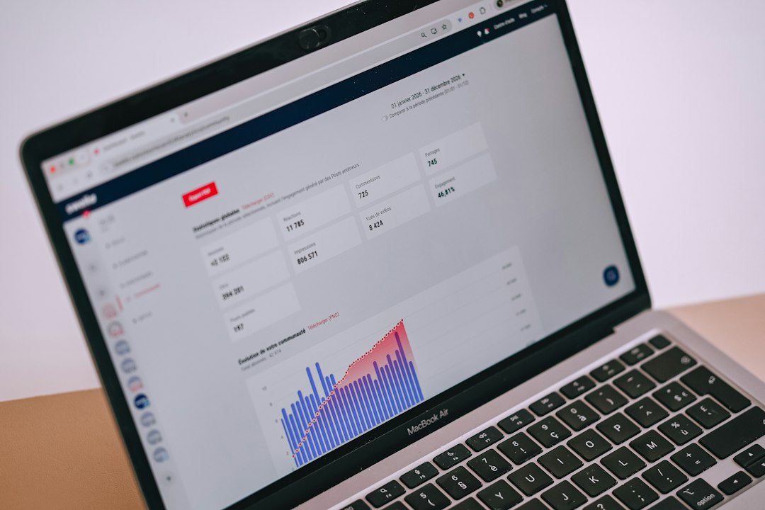 Laptop screen showing a data analytics dashboard with metrics cards and a colorful bar chart at the bottom edge (MacBook Air).
